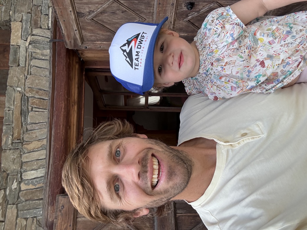 Lawrence holding his youngest daughter, who is wearing a Team DWIFT hat